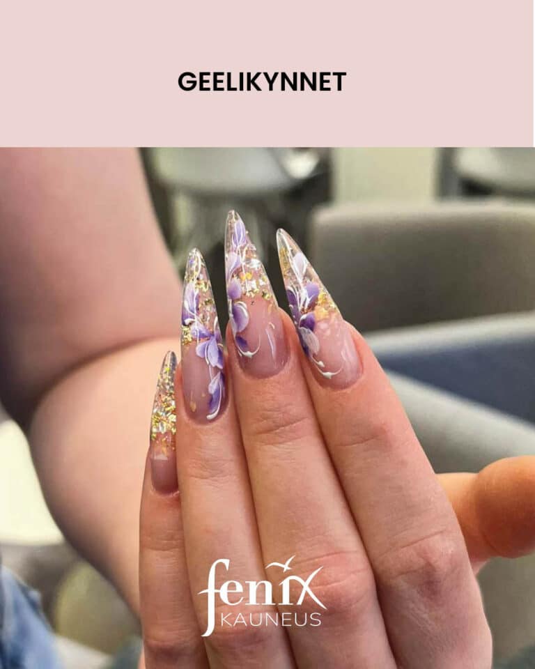 Lapinakyvat, pitkat, liloja kukkia ja kultahippuja sisaltavat, stiletto geelikynnet edestapain kuvattuna.