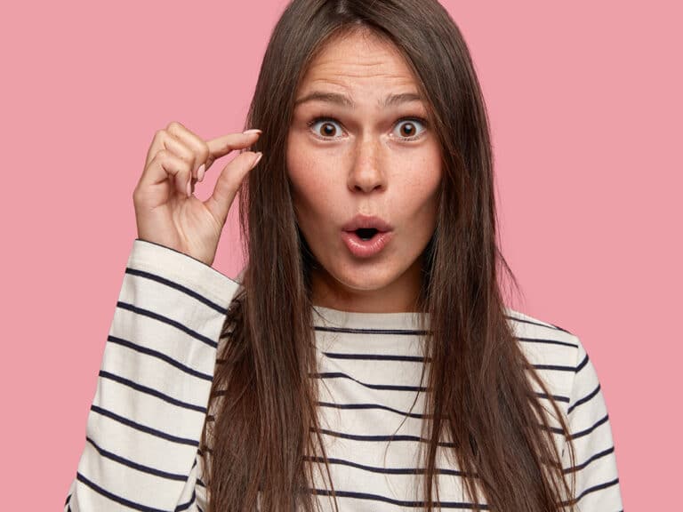 Nainen nayttaa peukalolla ja etusormella pikkuista valia.